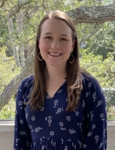 Abby smiling in a blue shirt outdoors