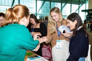 Attendees interacting with an exhibitor, who passes a resource to them.